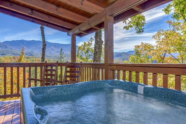 Un bain à remous sous une pergola en bois, avec vue sur la montagne.