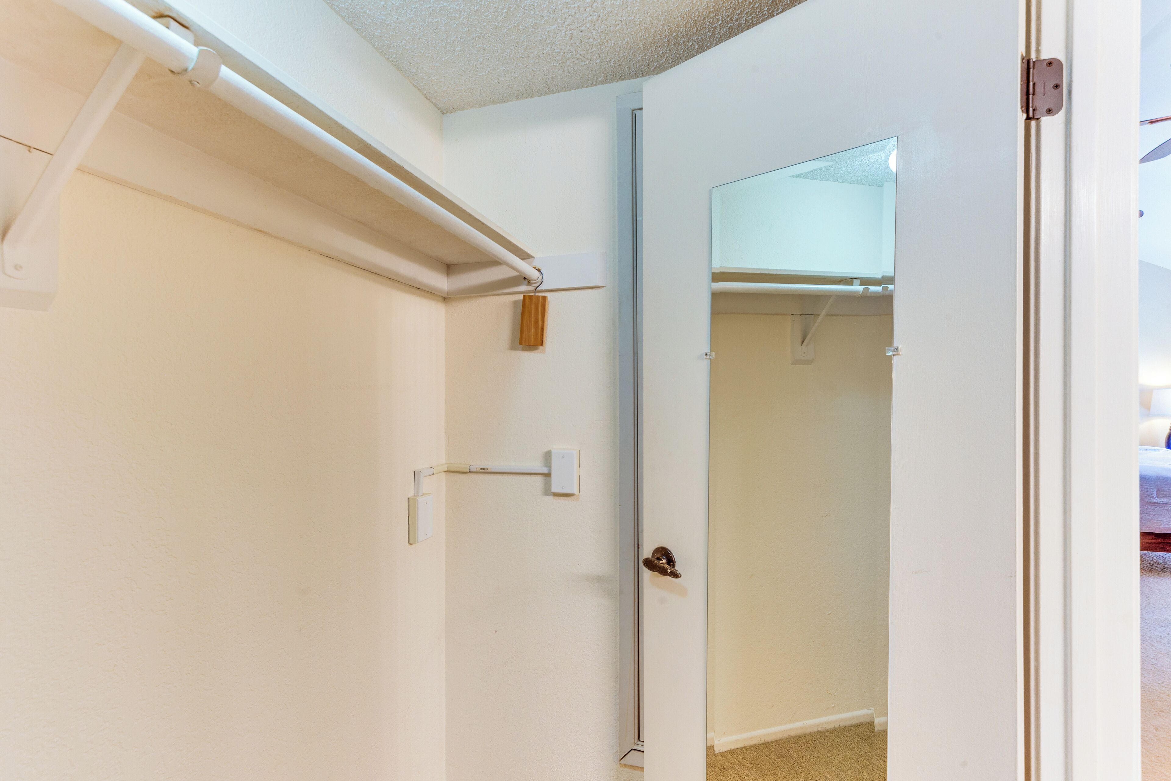 A room with a white door, a towel rack, and a mirror on the wall.