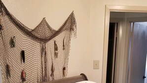 Een slaapkamer met een bed, een hoofdbord met een gaasachtig ontwerp en een quilt met een vispatroon.