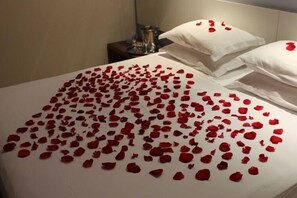 A bed with rose petals scattered on it. - Milla Hotel (Teixeira de Freitas)