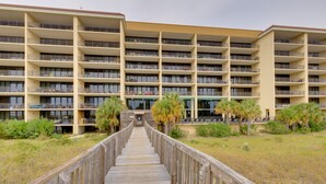 A multi-story hotel with a wooden walkway leading to the entrance. - Beach Access & Views: Dauphin Island Condo (Dauphin Island)