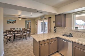 Una cucina con lavastoviglie, un'area pranzo con tavolo e sedie, e una ventola a soffitto.