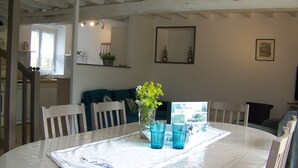 A dining area with a round table, chairs, a vase with flowers, and a welcome sign.