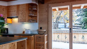 Een houten keuken met een inbouwfornuis, houten kastjes en een raam met uitzicht op een besneeuwde tuin.
