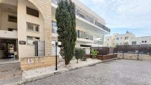 Un edificio residencial de varios pisos con fachada de piedra, balcones y un patio empedrado.