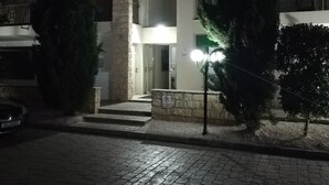 Una entrada de piedra con arco a un edificio de noche, con un cartel de estacionamiento, un coche y una farola.