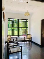 A room with a large window, a hanging light fixture, and a seating area with two chairs and a small table.