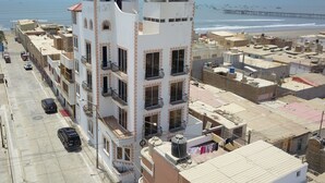 A multi-story building with balconies, a parking area, and a view of the beach and sea. - Blanca Rosa's Place Vacation Rentals (Pacasmayo)