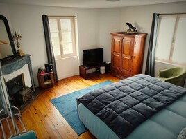 Un dormitorio con cama, televisión, armario, silla y chimenea.