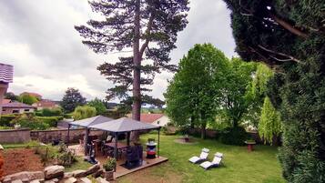 A backyard with a gazebo, lounge chairs, and a barbecue area.