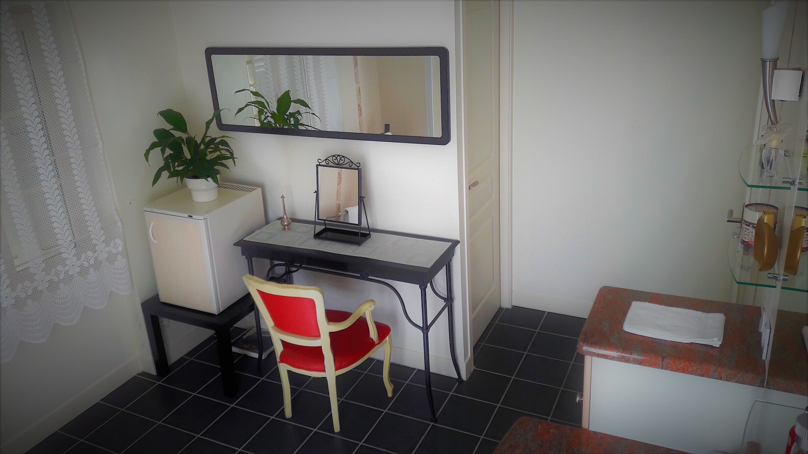 A compact room with a desk, chair, and a small refrigerator.