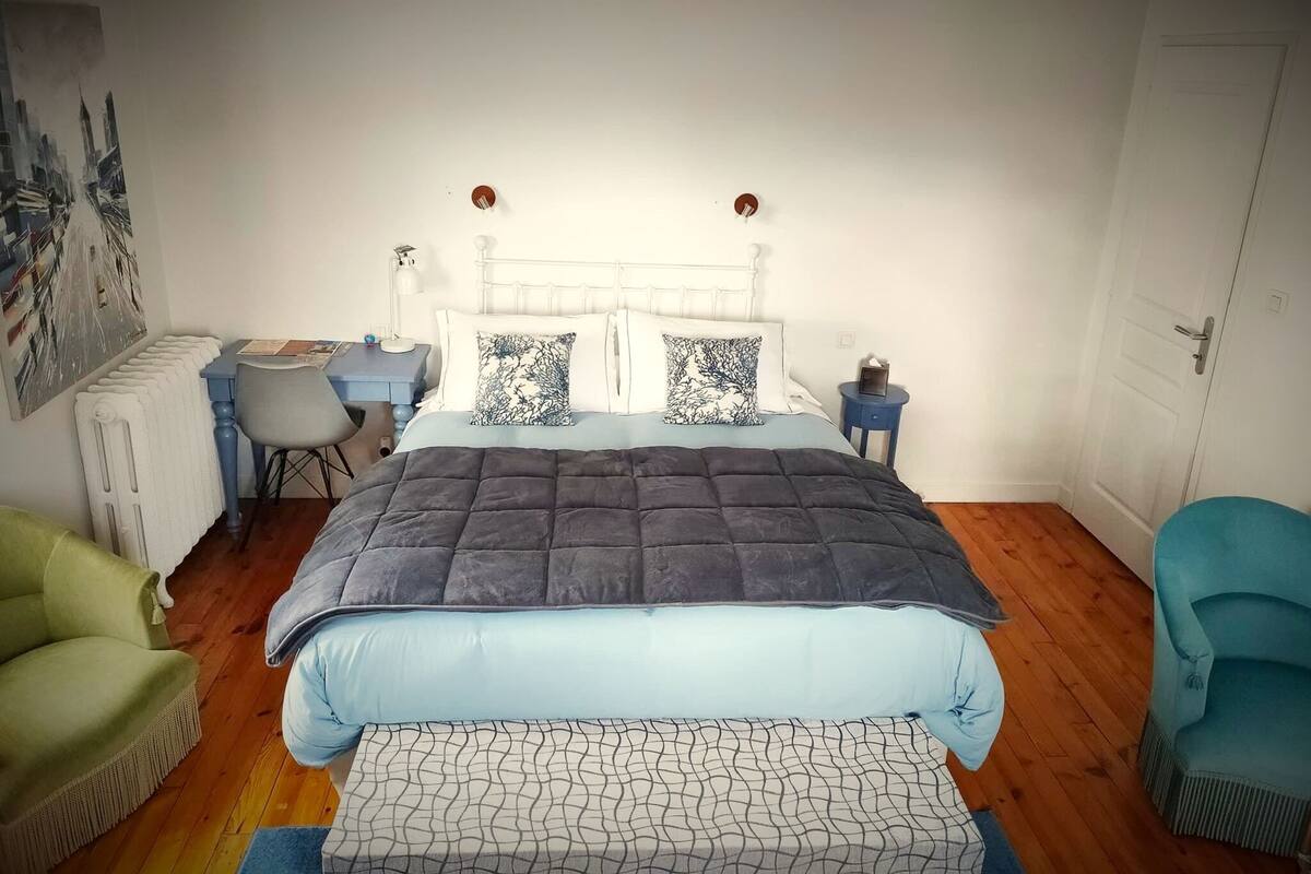 A bedroom with a bed, a desk, a chair, and a radiator.