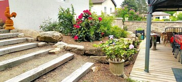 Un jardín con escalones que conducen a un patio amueblado al aire libre.
