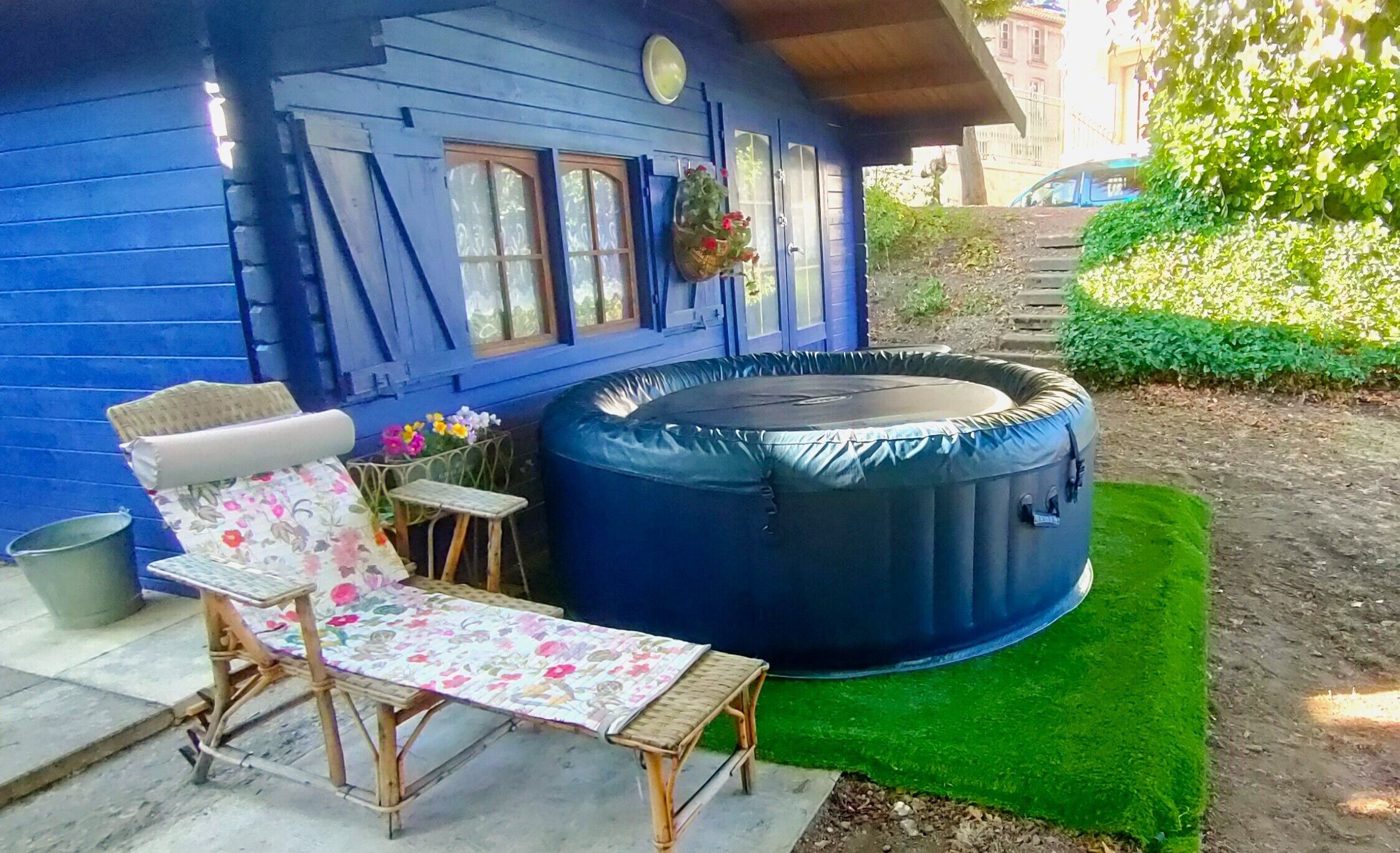 Een blauw huis met een jacuzzi, een lounge stoel en een klein tafeltje.