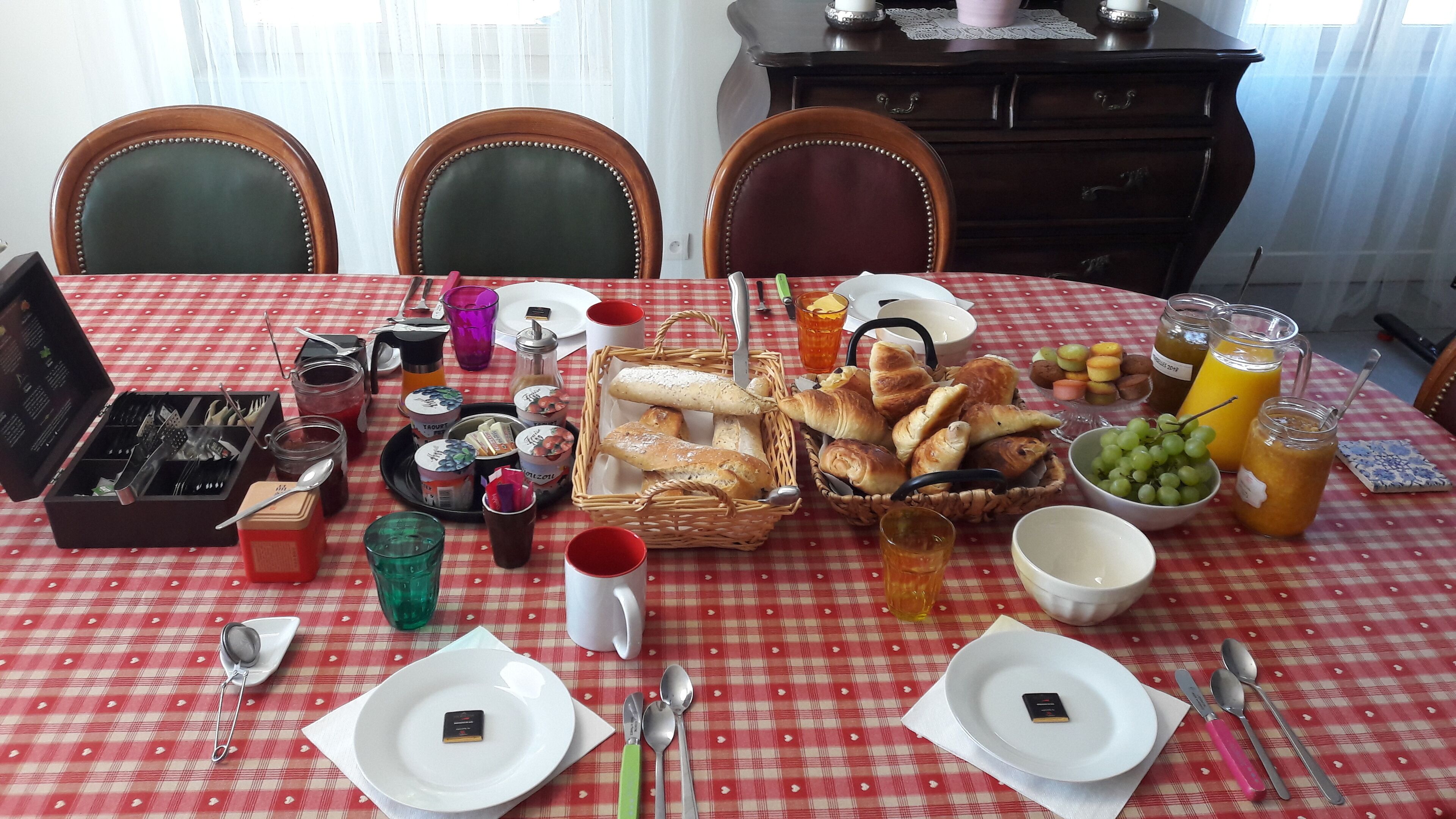 Una mesa de comedor dispuesta con diferentes alimentos, utensilios y bebidas.
