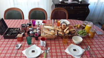 Una mesa de comedor dispuesta con diferentes alimentos, utensilios y bebidas.