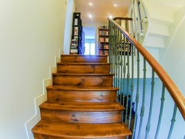 Una escalera de madera con barandilla de metal que lleva a una puerta en la parte superior.