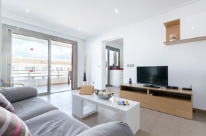 Relax in this stylish living room with a large flat-screen TV, comfortable sofa, and balcony access.