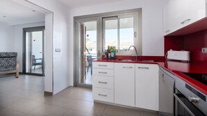 Una cucina moderna con mobili bianchi, un piano di lavoro rosso e una lavastoviglie.