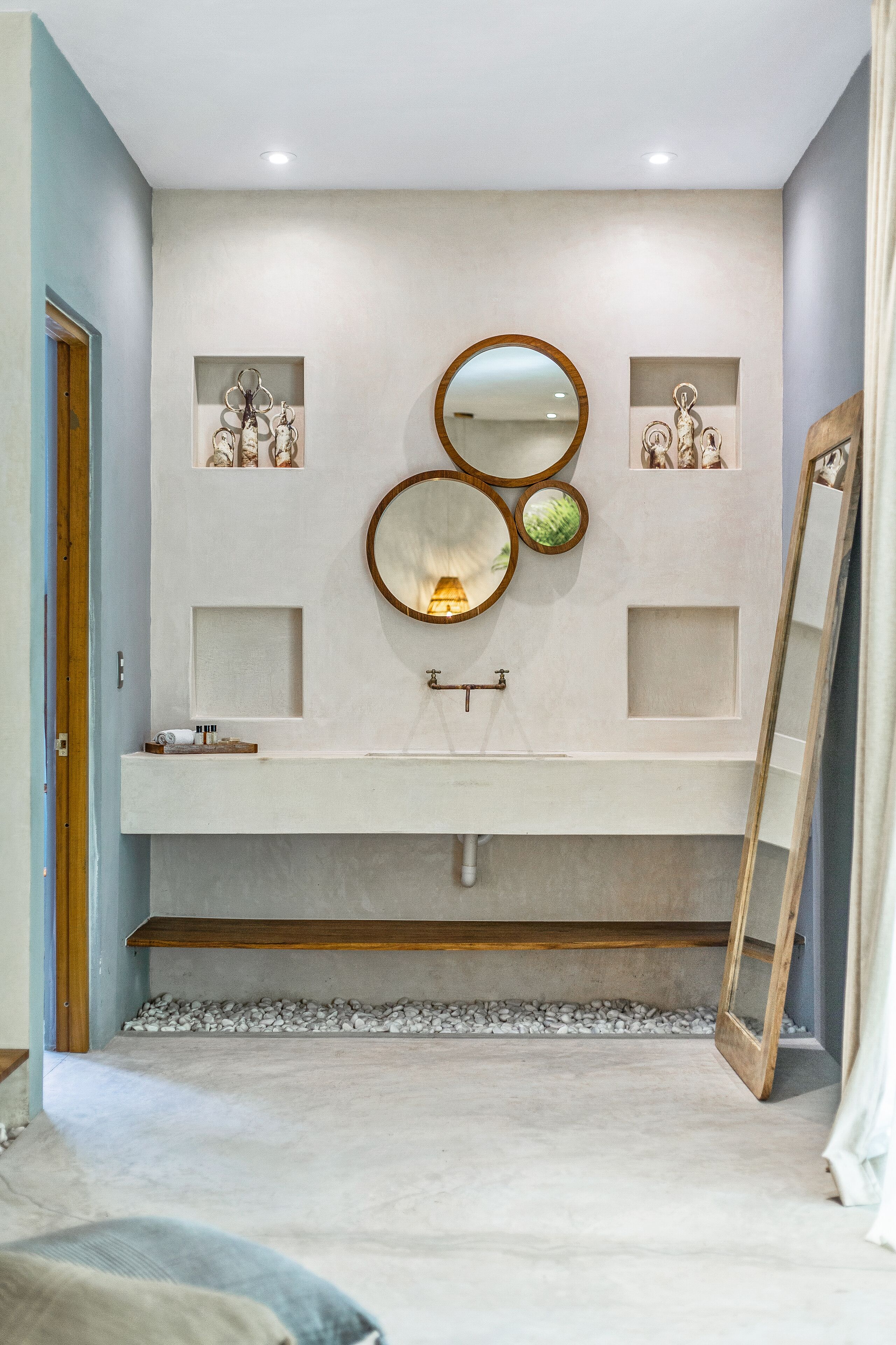 Un baño con un espejo grande, un lavabo y detalles decorativos en la pared.