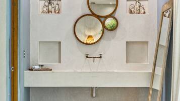 Un baño con un espejo grande, un lavabo y detalles decorativos en la pared.