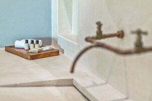 Een badkamer met een houten dienblad waarop toiletartikelen, een handdoek en een raam met uitzicht liggen.