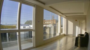 A spacious hallway with large windows, a trash bin, and a door. - Grande Hotel (Gurupi)