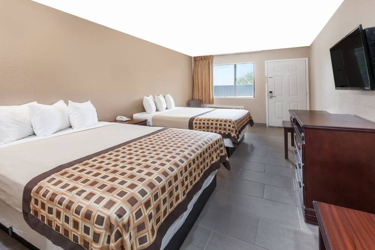 A hotel room with two beds, a TV, a desk, and a wardrobe.