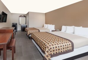 Habitación de hotel con dos camas, un escritorio de madera, un espejo, un microondas y un lavabo.