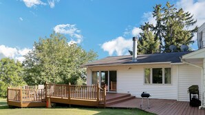A single-story house with a covered deck, a chimney, and satellite dishes.