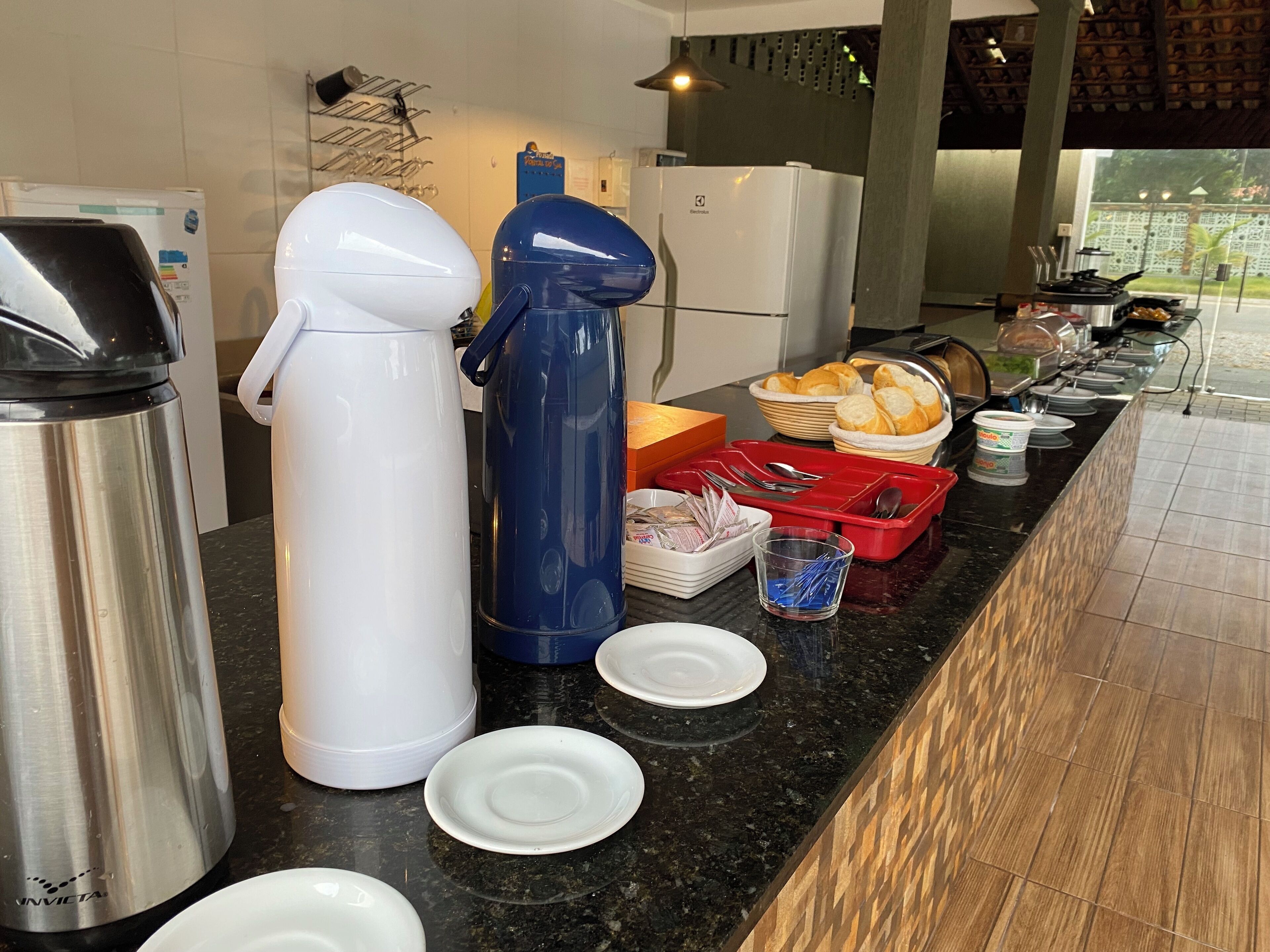 Montaje de un bufé de desayuno con diversos alimentos y utensilios.