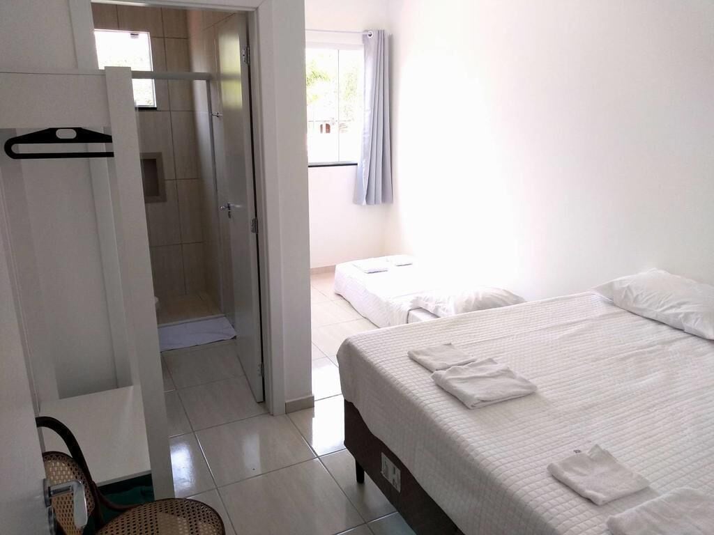 A hotel room with a bed, a shower area, and a wardrobe.