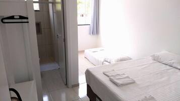 A hotel room with a bed, a shower area, and a wardrobe.