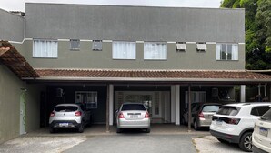 A two-story building with a covered garage housing four cars. - Pousada Pontal do Sul (Pontal do Parana)