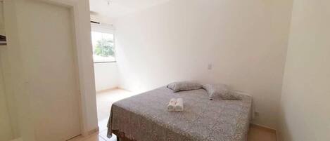 A bedroom with a bed, a pillow, and a pair of slippers on the bed.