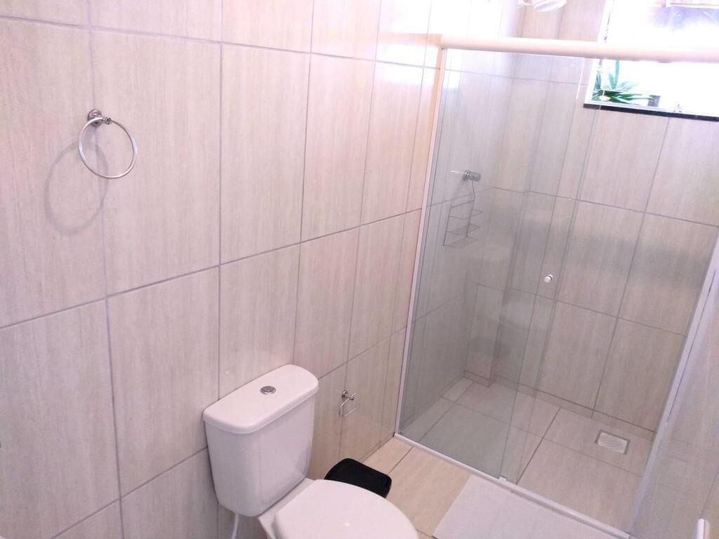 Casa de banho com sanita, cabine de duche e porta de vidro.