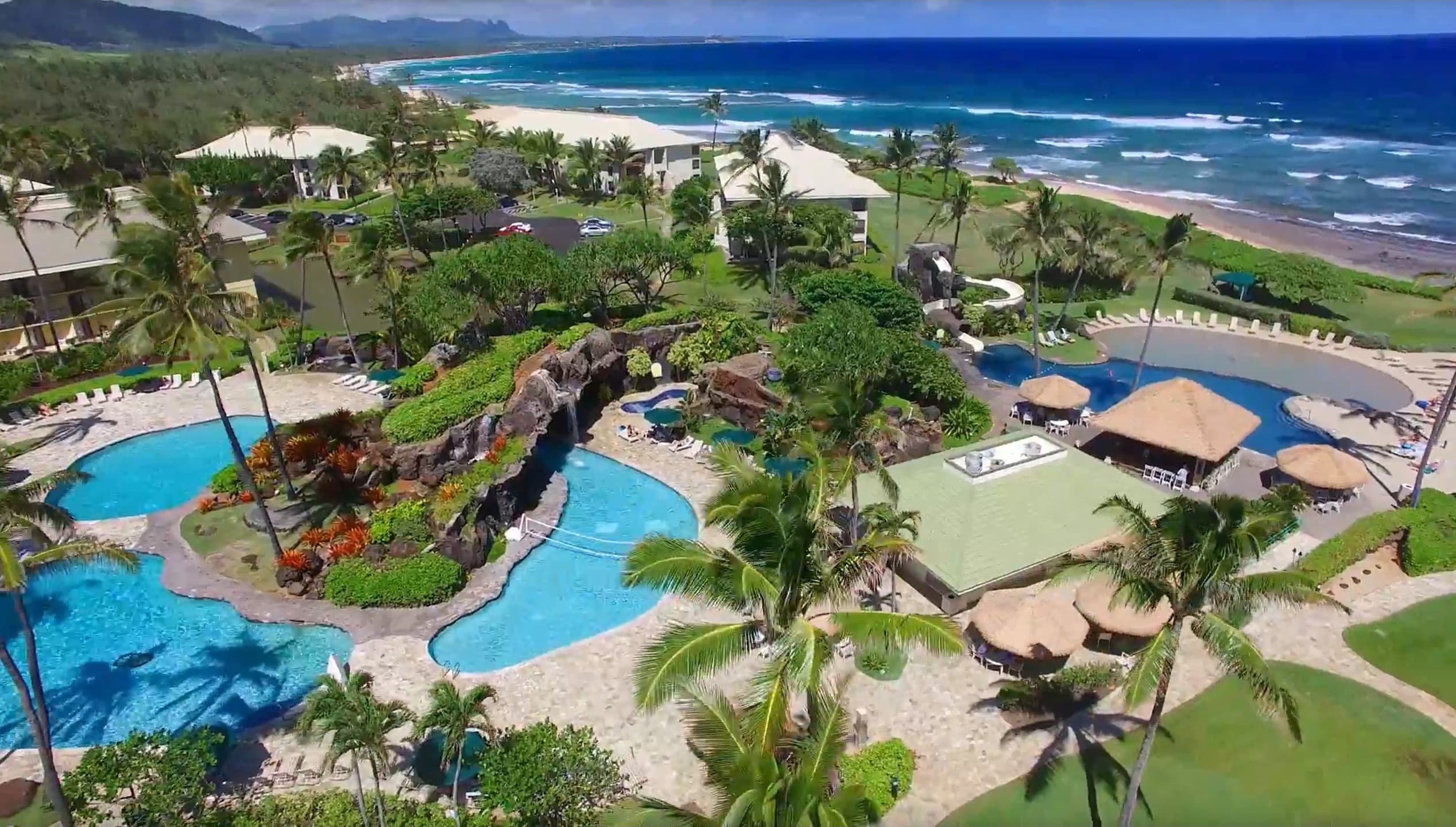 A resort with multiple swimming pools, a beach, and a view of the ocean.