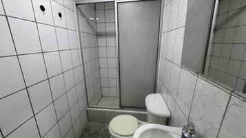 A small, tiled bathroom with a toilet, a sink, and a shower stall.
