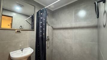 Un bany amb un lavabo blanc, un mirall i una dutxa amb cortina negra.