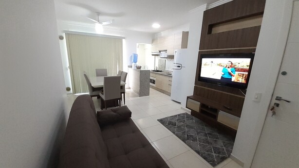 A modern living room with a brown sofa, a television, and a kitchen in the background. - 318, Great Value 3-Bedroom Apartment (Bombas)