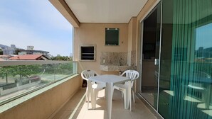A balcony with a white table and chairs, a small window, and a view of buildings. - 318, Great Value 3-Bedroom Apartment (Bombas)