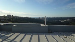 Una terraza en la azotea con vistas a un paisaje urbano y colinas lejanas.