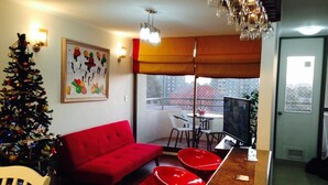 Una sala de estar con un sofá rojo, un árbol de Navidad y un comedor con mesa y sillas.