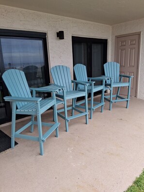 A set of four light blue Adirondack chairs arranged around a small table on a concrete patio.