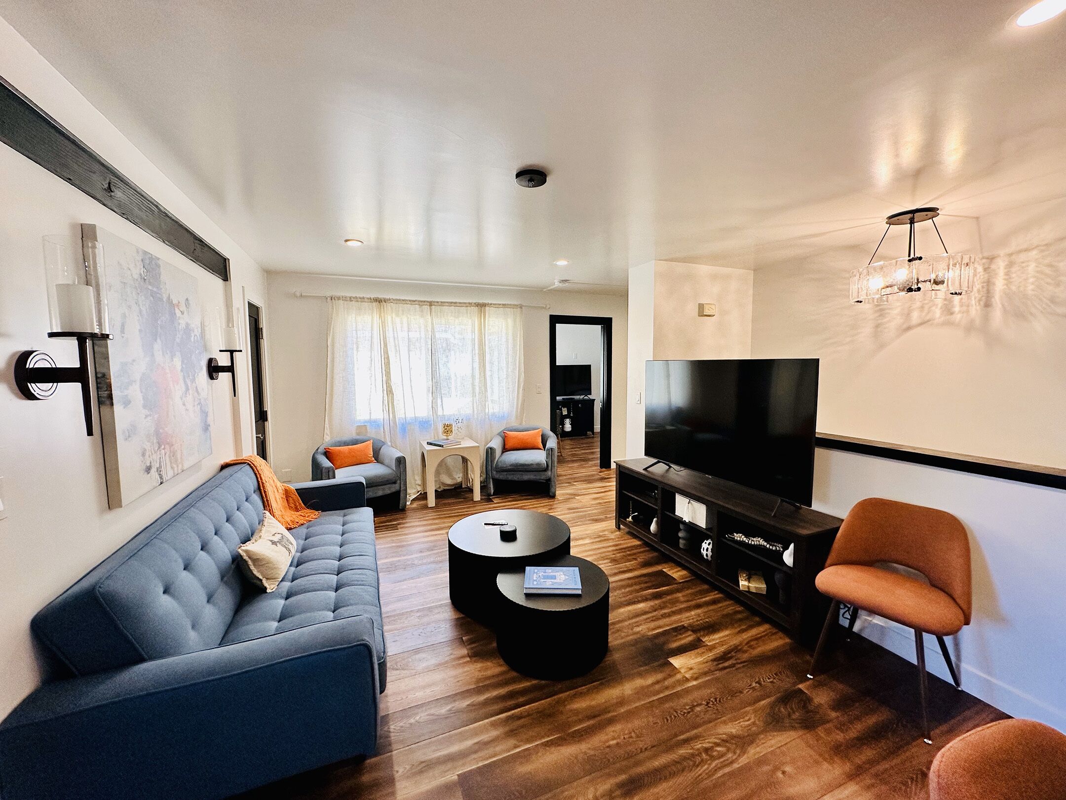 Una sala de estar moderna con sofá, mesa de centro, televisor y comedor.