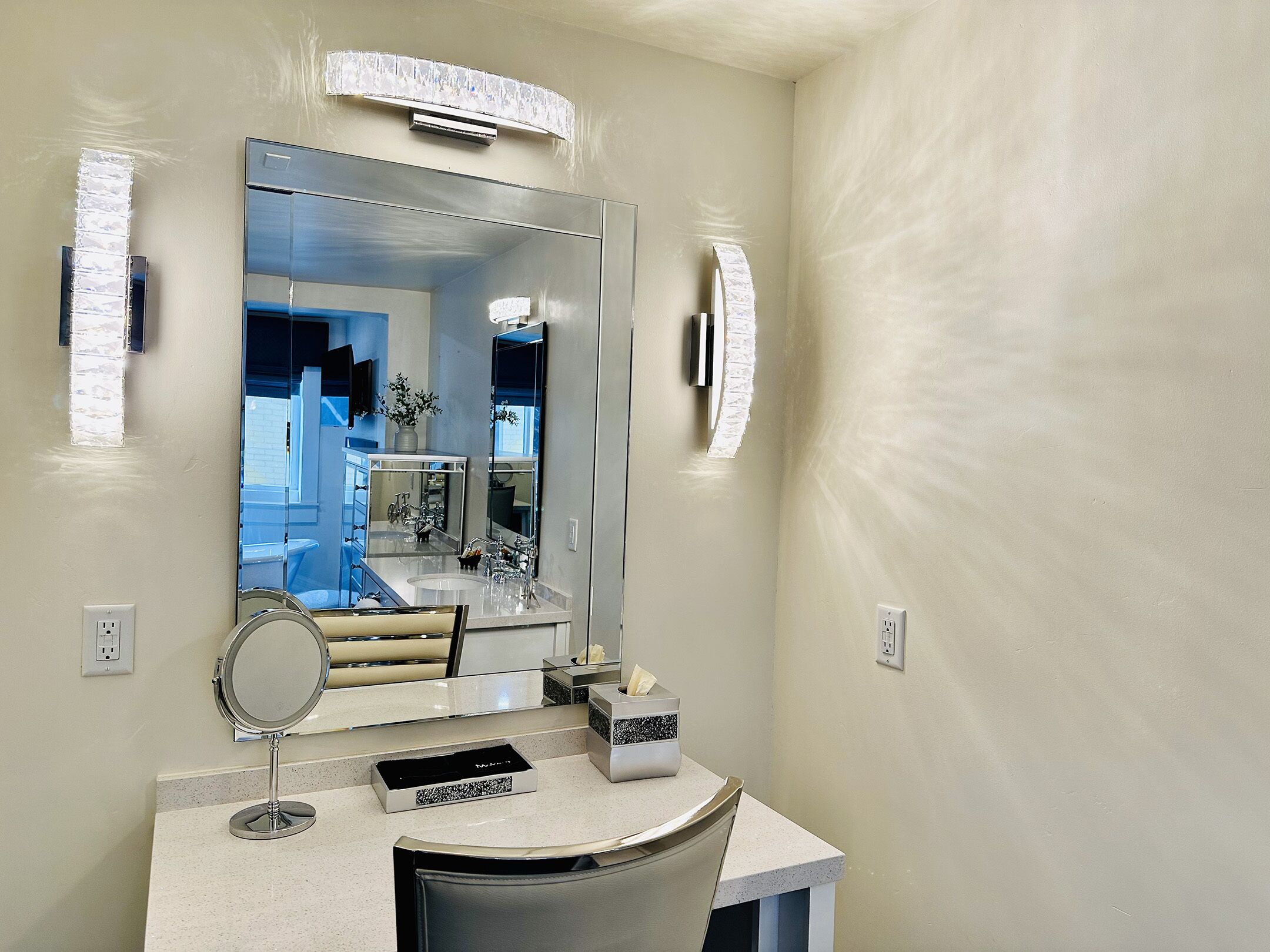 A bathroom with a large mirror, a vanity with a sink, and a towel rack.
