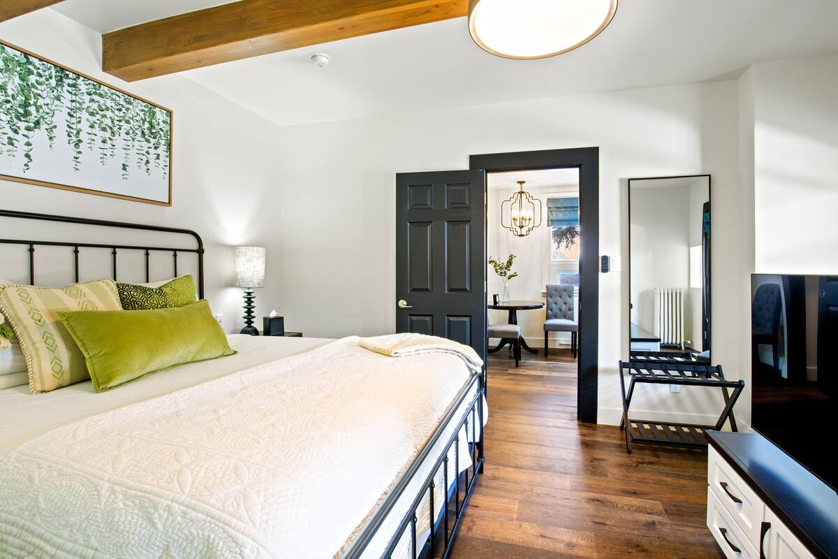A bedroom with a bed, bedside table, lamp, and a mirror.