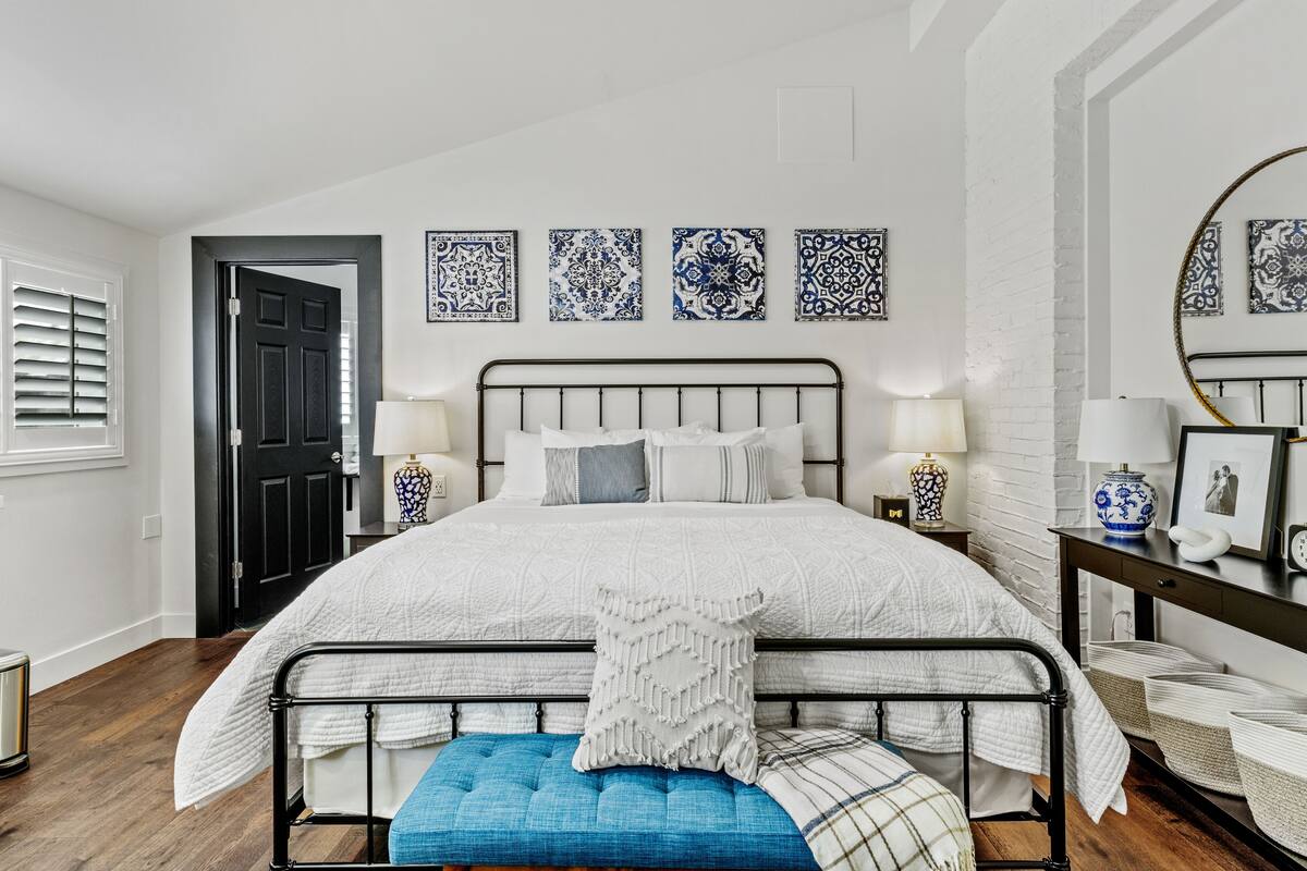 A bedroom with a bed, bedside tables, a mirror, and wall decor.