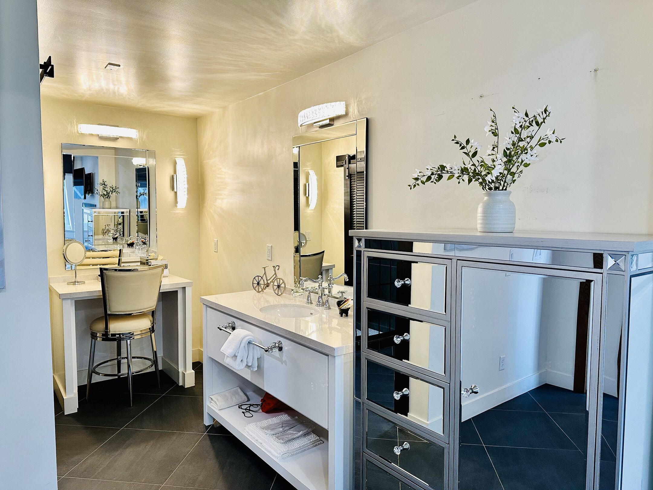 A modern bathroom with a large mirror, a vanity with a sink, and a chair.