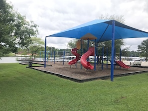 A playground with a red slide and a blue canopy.